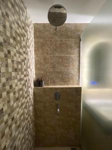 y baño con ducha y pared de piedra. en The yudhistira apartment en Yogyakarta