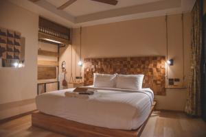 um quarto com uma grande cama branca e uma parede de tijolos em Gategaa Village em Chiang Mai