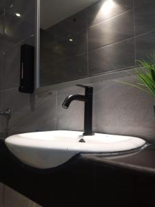 La salle de bains est pourvue d'un lavabo, d'un robinet et d'un miroir. dans l'établissement ezzahrahsyariahhomestay, à Sandakan