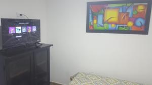 a television sitting on a stand next to a painting at cerca club militar Corferias, embajada americana 501 in Bogotá