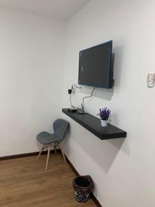 a desk with a chair and a tv on a wall at Hi TechSTAY in Lunas