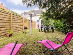einen Hinterhof mit rosa Stühlen, einem Tisch und einem Zaun in der Unterkunft Gîte Saint-Lyphard, 3 pièces, 4 personnes - FR-1-306-1163 in Saint-Lyphard