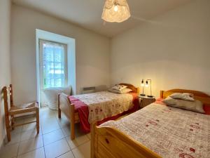 1 dormitorio con 2 camas, silla y ventana en Gîte Alleyrac, 4 pièces, 6 personnes - FR-1-582-66, en Alleyrac