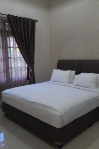 a bed with white sheets and pillows in a bedroom at KoolKost At Tenggilis - Minimum Stay 30 Nights in Tenggilismedjojo