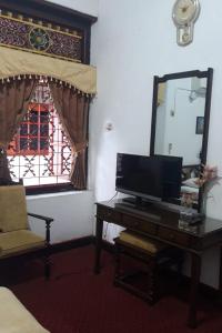 a room with a mirror and a desk with a television at KoolKost At Tenggilis - Minimum Stay 30 Nights in Tenggilismedjojo
