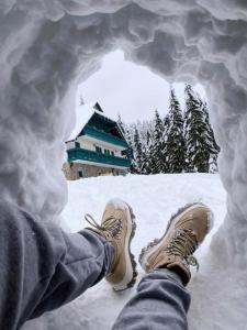 uma pessoa com os pés numa abertura na neve em Apartma Bellevue Rogla em Vitanje