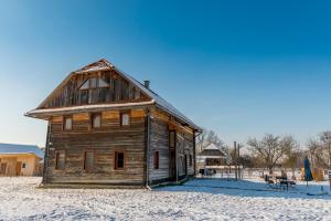 an old wooden house in a snowy field with snow at Wooden Barn in Zăbala
