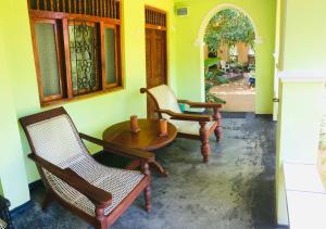 Habitación con 3 sillas y mesa de madera. en Temple Flower Guest, en Kirinda