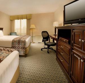 ein Hotelzimmer mit einem Bett und einem Schreibtisch mit einem Fernseher in der Unterkunft Hotel Lotus Kansas City Stadium in Kansas City