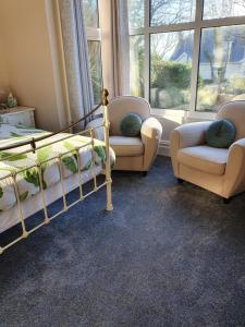 a bedroom with two bunk beds and two chairs at Chynoweth Lodge in Newquay