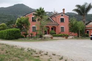 una casa rosa con palmeras y entrada en Agriturismo Agri Mediterraneo, en Capaccio-Paestum