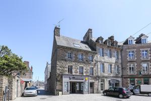 un antiguo edificio de piedra en una calle con coches aparcados en Le Martray - Appartement coeur historique de Paimpol, en Paimpol