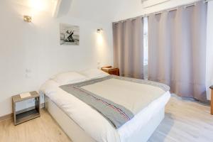 a white bedroom with a bed and a window at Le Martray - Appartement coeur historique de Paimpol in Paimpol