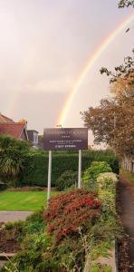 a rainbow in the sky over a sign in a yard at Chynoweth Lodge in Newquay