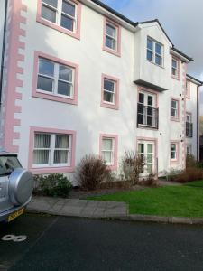 凯西克Keswick Ground floor apartment with parking的白色的房子,有粉红色的窗户,前面有停车位