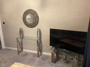 a living room with a tv and a glass table at holiday apartment in Ardrossan