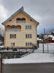 a large yellow house with a fence in front of it at Casa Giorgiana in Statiunea Borsa