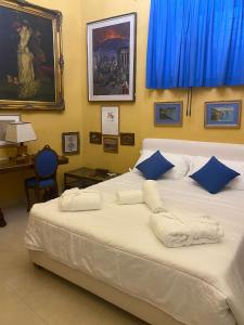 una camera da letto con un grande letto bianco con cuscini blu di Sunlux Maison a Ischia