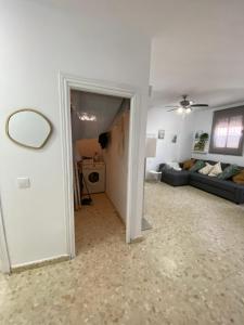 a hallway of a living room with a couch and a mirror at Precioso apartamento en el centro de Conil para familias, parejas y grupos in Conil de la Frontera