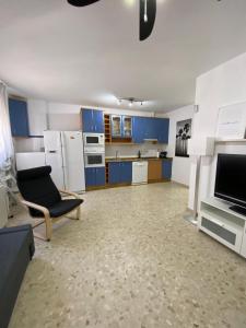 a kitchen with blue cabinets and a couch and a chair at Precioso apartamento en el centro de Conil para familias, parejas y grupos in Conil de la Frontera