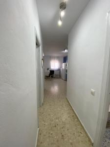 Precioso apartamento en el centro de Conil para familias, parejas y grupos في كونيل دي لا فرونتيرا: ممر فارغ مع جدار أبيض وكرسي +صورة واحدة
