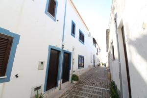an alley with white buildings and blue doors at Fisherman's Townhouse at Old Town in Albufeira