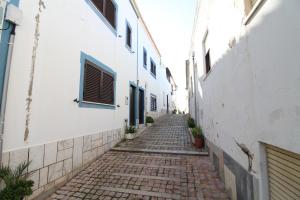 an alley with white walls and a cobblestone street at Fisherman's Townhouse at Old Town in Albufeira +2 photos