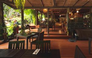 een restaurant met tafels en stoelen op een houten terras bij Sukantara Cascade Resort and Spa in Mae Rim