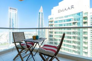 a table and chairs on a balcony with a view of the city at Vacay Lettings - Loft Downtown Dubai in Dubai