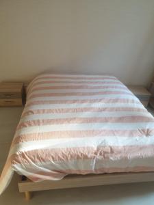 ein Bett mit einer rosa und weißen Decke darauf in der Unterkunft Appartement 4 couchages in Clairvaux-les-Lacs