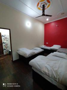 a room with two beds and a red wall at Stayble Homestay in Dehradun
