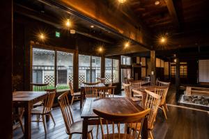 un ristorante con tavoli e sedie in legno e un camino di Satoyama Villa Honjin a Matsumoto