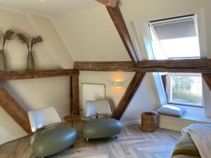 a attic room with two chairs and a window at B&B Idylle aan Zee incl 2 Wellnessstudios in Sint Maartensvlotbrug
