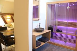 een badkamer met een wastafel en een douche met paarse verlichting bij B&B Idylle aan Zee incl 2 Wellnessstudios in Sint Maartensvlotbrug