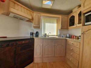 cocina con armarios de madera, fregadero y lavavajillas en 'Runway View' at Shobdon Airfield, Herefordshire en Shobdon