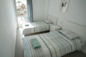 two beds in a room with a window at Modern sea view duplex with parking in El Médano