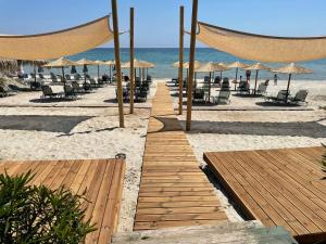 a boardwalk on the beach with chairs and umbrellas at Green Sea Apartments in Skala Potamias