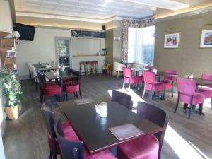 una sala da pranzo con tavoli e sedie rosa di Arrandale House a Douglas