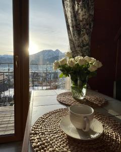 una mesa con una taza y un jarrón de flores en el balcón en Wczasy Pod Giewontem, en Kościelisko
