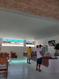 two men standing in a kitchen preparing food at Paraiso Barra Hotel in Barra de Santo Antônio