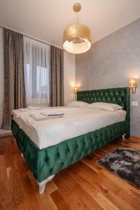 a bedroom with a large bed with a green headboard at Apartman Istra- Titova vila in Zlatibor