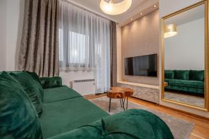 a living room with a green couch and a mirror at Apartman Istra- Titova vila in Zlatibor