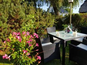 una mesa y sillas en un jardín con flores rosas en Hotel Schleimünde, en Kappeln