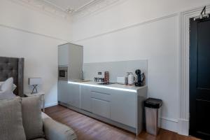 a kitchen with white cabinets and a couch in a room at Casa Fresa - Orchar Suites in Broughty Ferry