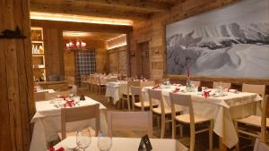 un ristorante con tavoli e sedie bianchi e un grande dipinto di RESORT VALFORMICA ad Asiago