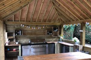 an outdoor kitchen with a stove and a wooden ceiling at Stunning Oxfordshire 5 Bedroom House in 2 acres in Aston Rowant