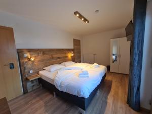 een slaapkamer met een groot bed met een houten hoofdeinde bij Hotel Pension Annerlhof in Maria Alm am Steinernen Meer