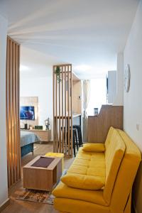 a living room with a yellow couch and a kitchen at TeonaLux Kraljevi Cardaci 5a/22 in Kopaonik