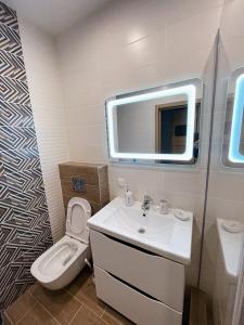 La salle de bains est pourvue d'un lavabo, de toilettes et d'un miroir. dans l'établissement Апартаменты NEO в жк Империал, à Trouskavets