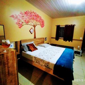 a bedroom with a bed with a tree painted on the wall at Casal.20 Studios Flats in Cabo de Santo Agostinho